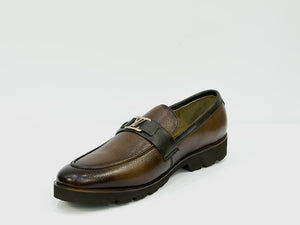 A brown leather loafer with a dark brown strap featuring a gold-tone LV monogram logo, set against a plain light gray background.
